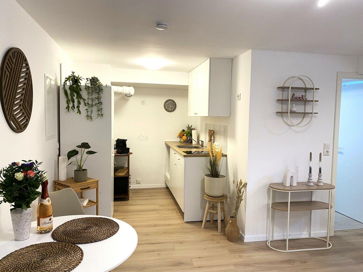 Küche mit Arbeitsplatte, Schränken und Pflanzen. Essbereich mit Tisch und Stühlen.