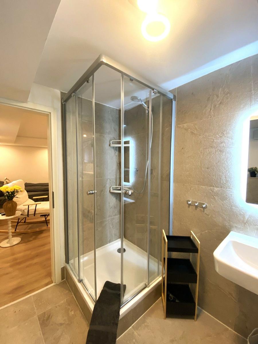 Duschkabine mit Glaswand, Waschbecken und Spiegel