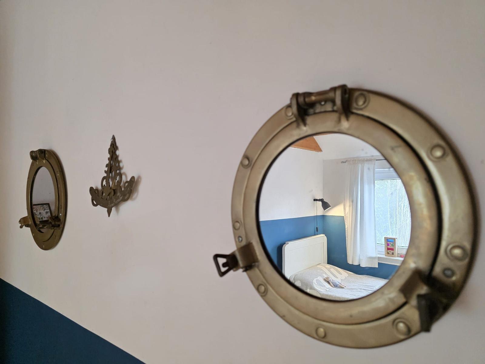 Room with view through round window, bed and window with curtain.