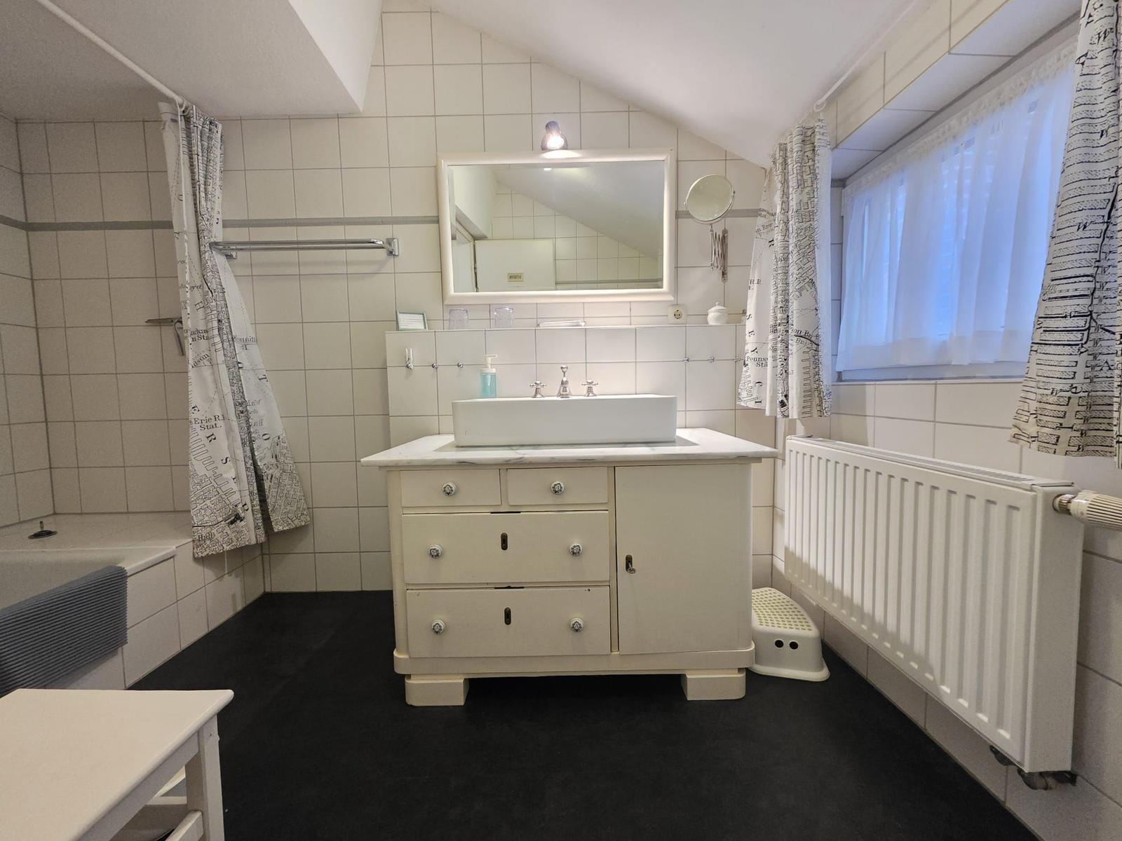 Bathroom with sink, mirror, and shower under sloped ceiling.