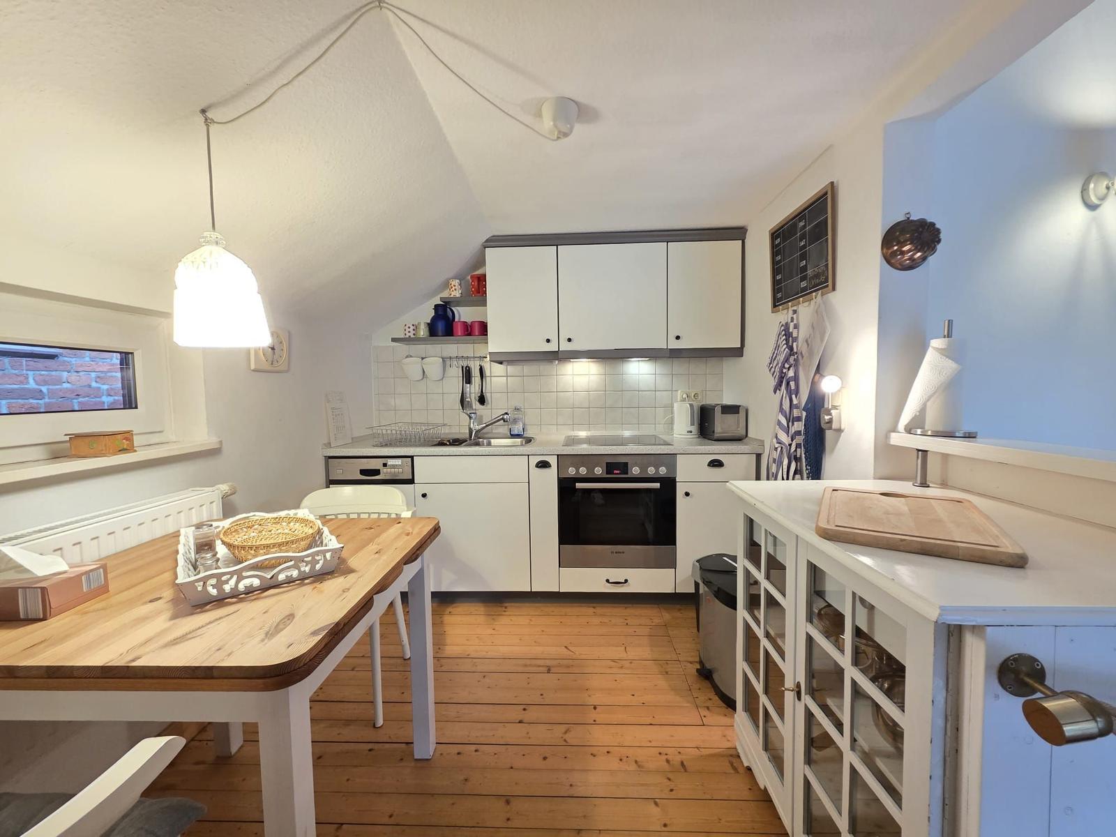 Kitchen with dining area, wooden floor, and white cabinets.