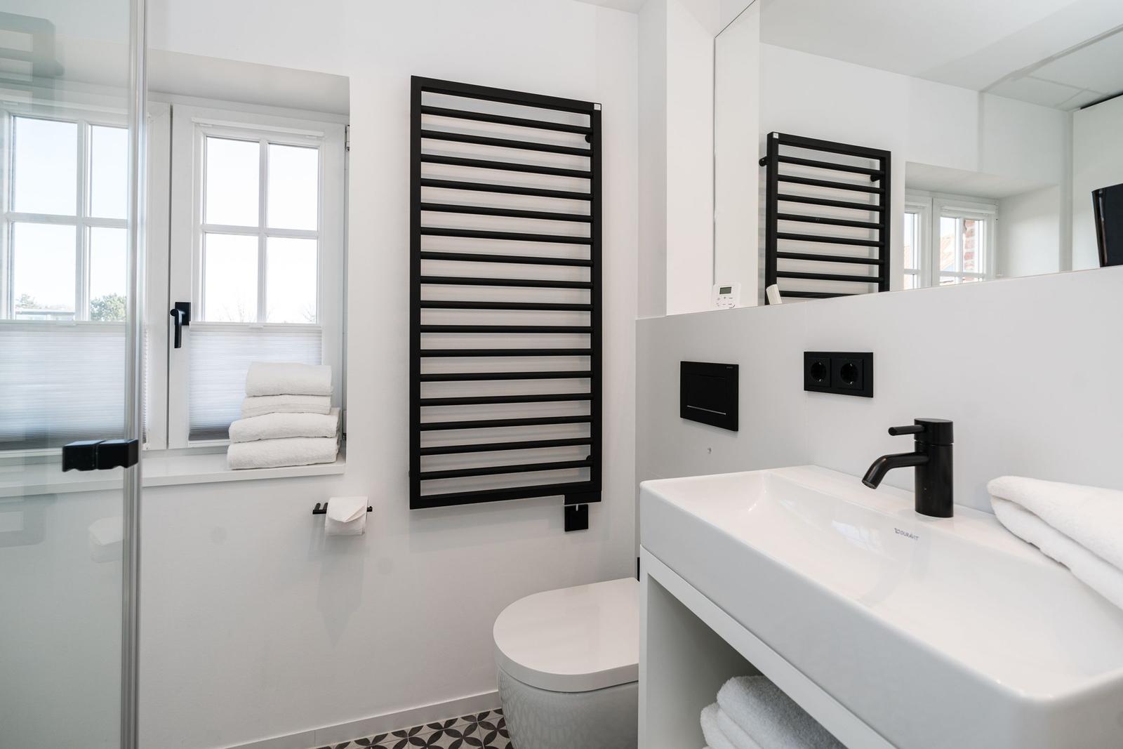 Moderne Badezimmer mit Dusche, Waschbecken und Heizkörper.