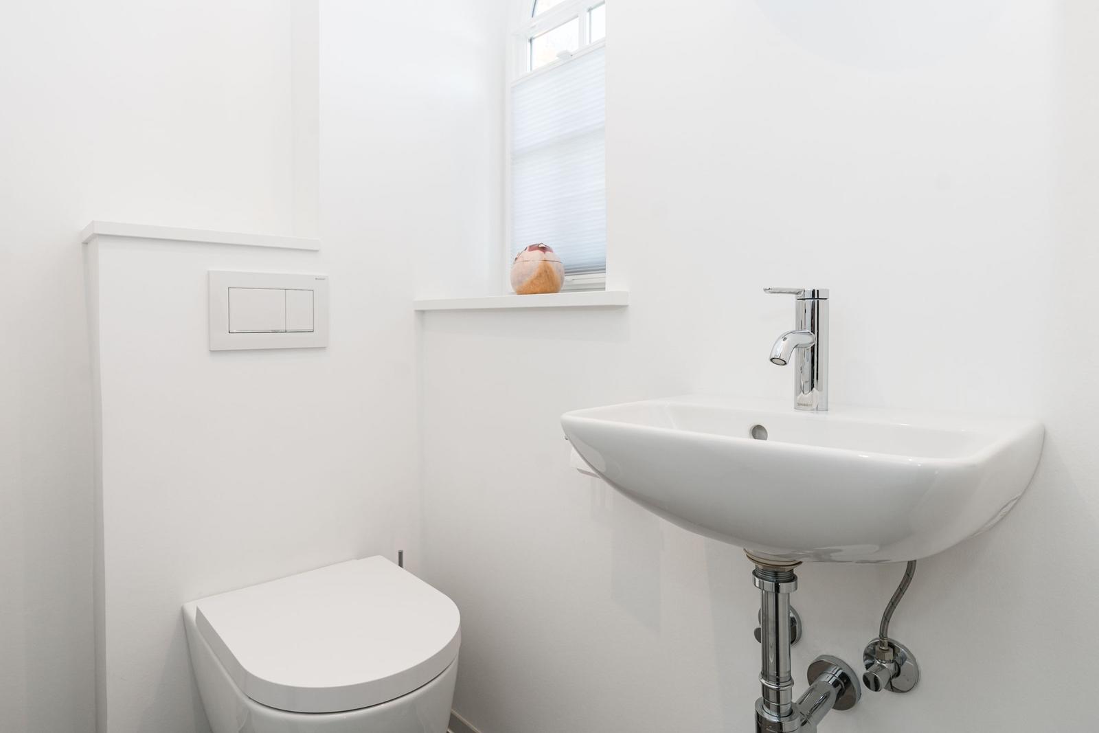 Badezimmer mit Toilette, Waschbecken und Fenster