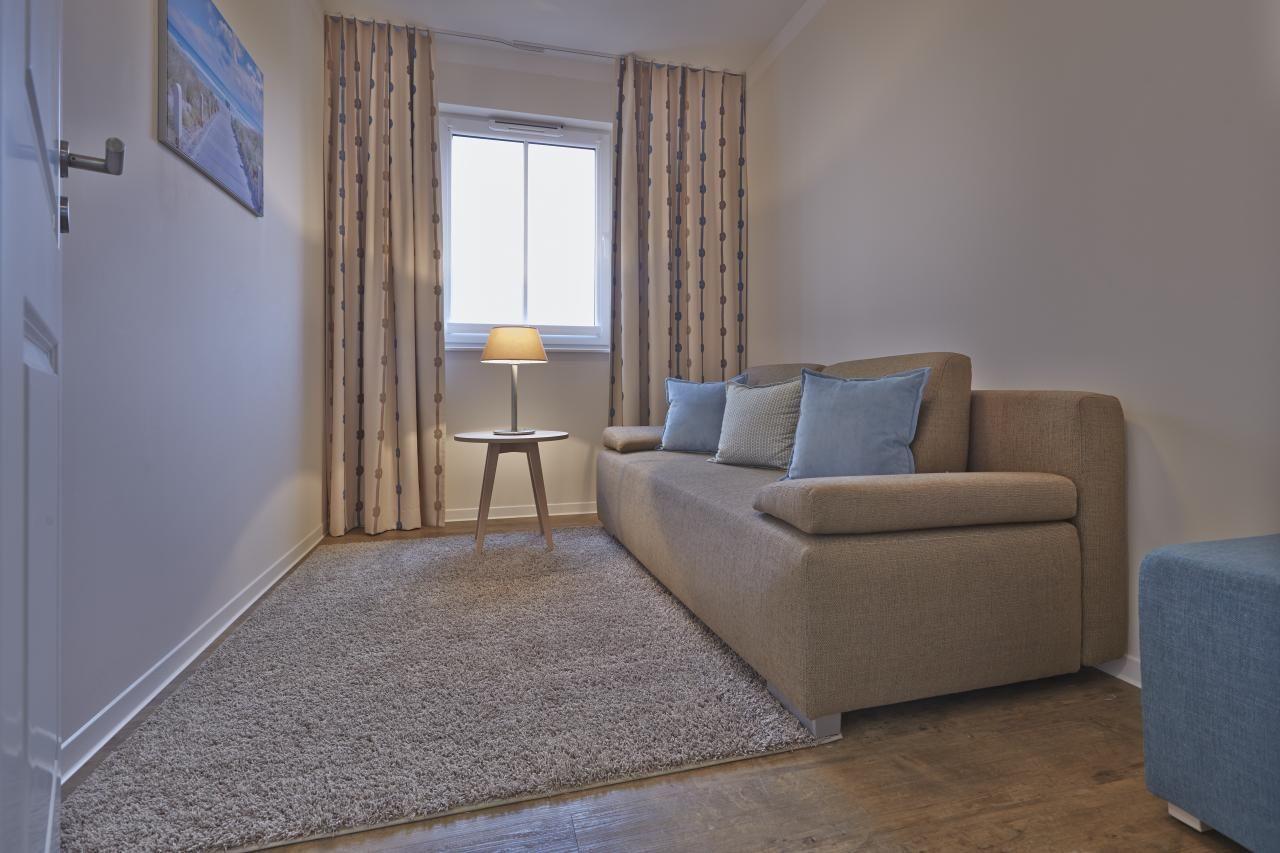 Ein Wohnzimmer mit Sofa, Vorhängen und Lampe neben dem Fenster.