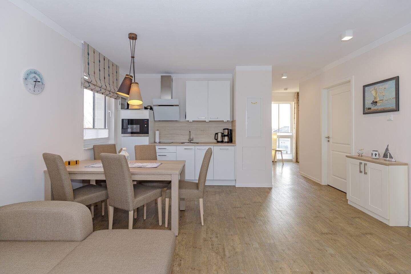 Essbereich mit Tisch, Stühlen und Küchenzeile im Hintergrund.