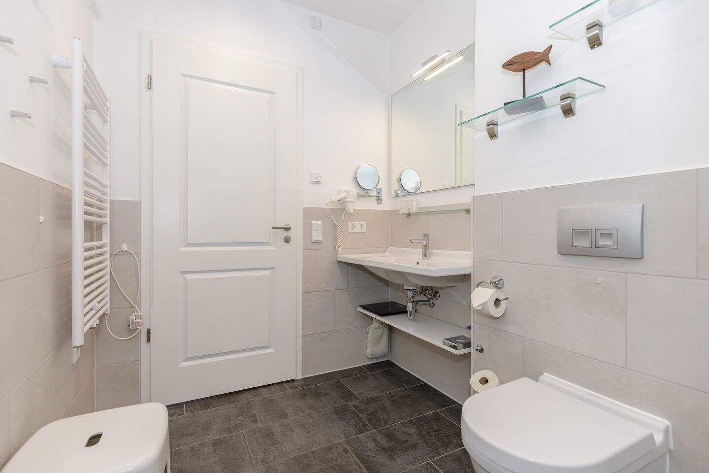 Badezimmer mit Waschbecken, Toilette und Heizung.