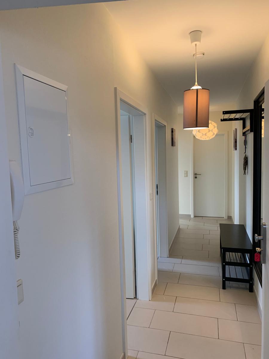 Flur mit Tür zu Schlafzimmer, Hängelampe und Bänkchen