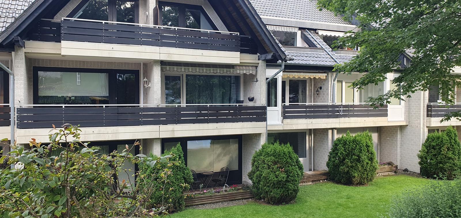 Ferienhaus mit Balkonen und Garten. Modernes Gebäude mit großen Fenstern.