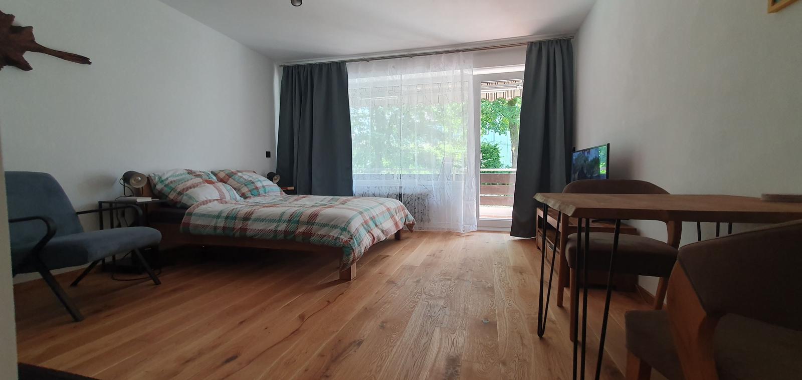 Schlafzimmer mit Bett, Tisch, Stühlen und Balkonansicht.