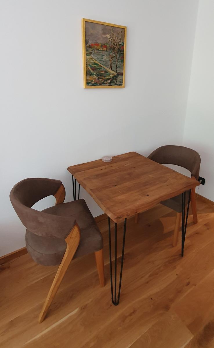 Holztisch mit zwei Stühlen und Wandbild im Essbereich.