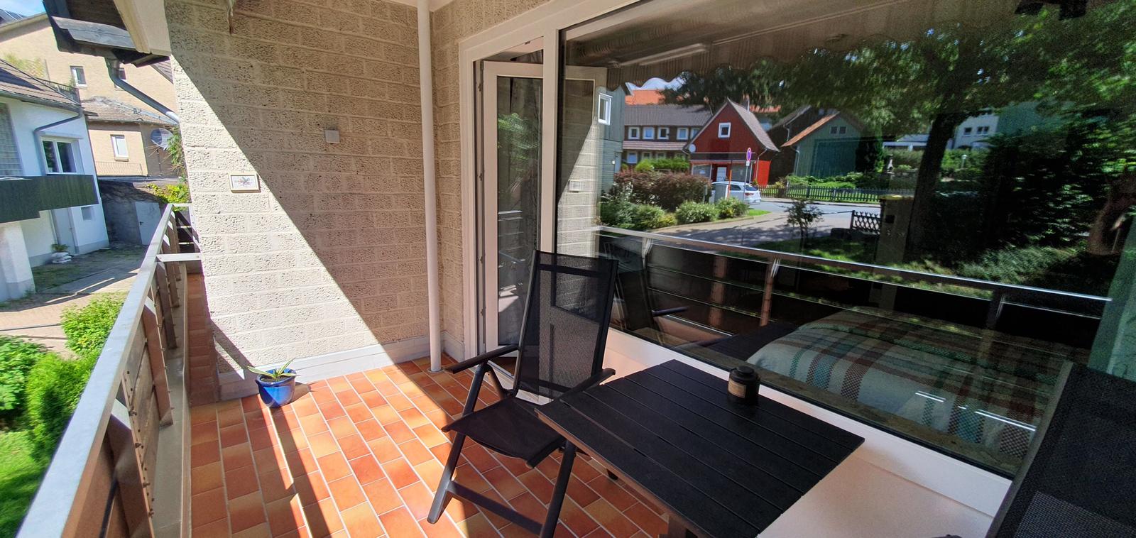 Terrasse mit Tisch und Stühlen, Blick auf Straße und Grünanlagen.