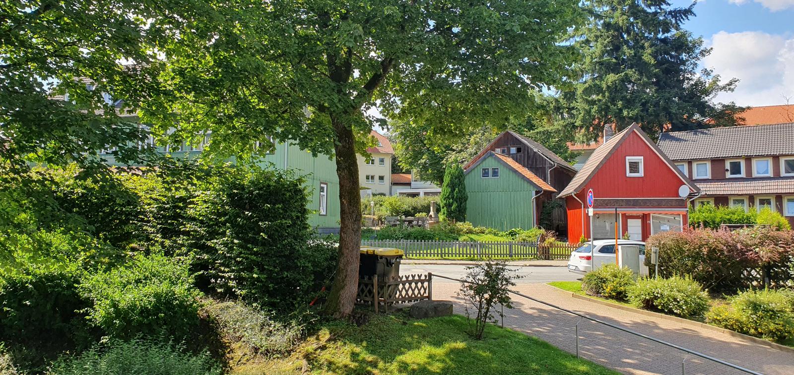 Rotes Haus mit Garten und Bäumen in ruhiger Straße