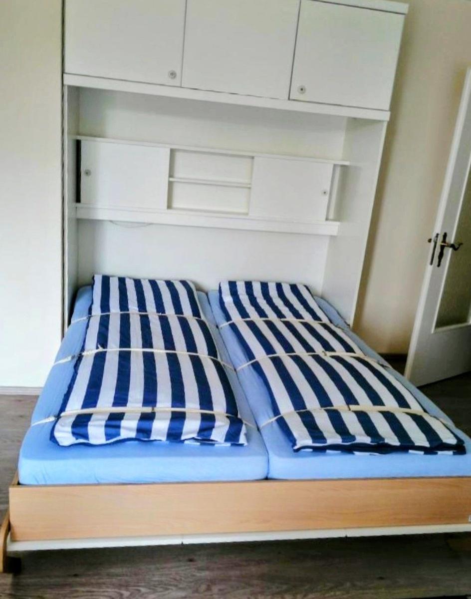 Zwei Betten mit blau-weiß gestreiften Bettwäsche unter einem weißen Schrank.