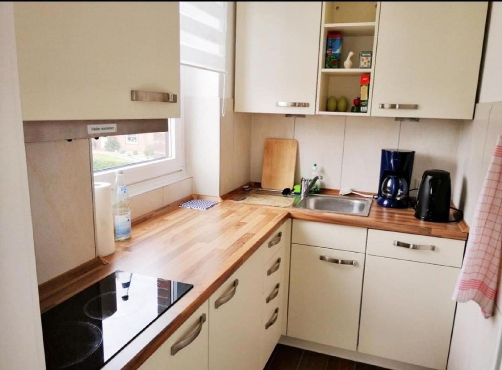 Küche mit Holzoberfläche, Spüle, Kaffeemaschine und Wasserkocher.