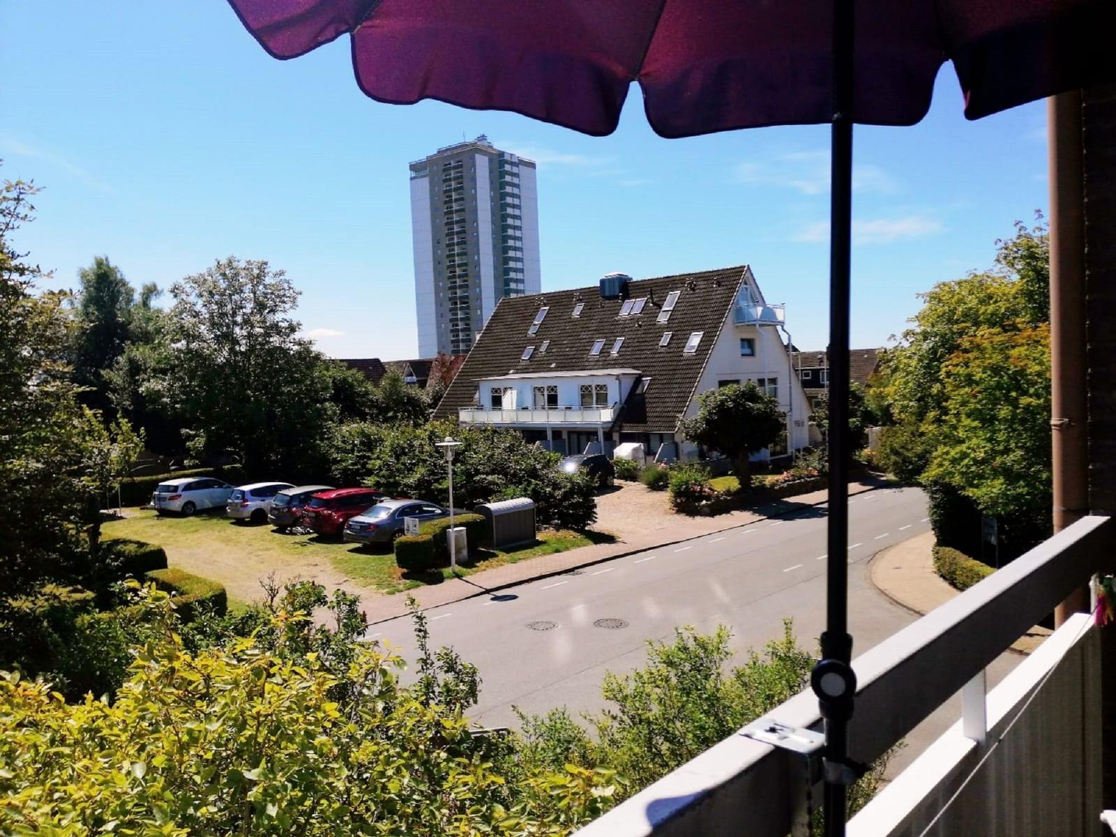 Blick vom Balkon auf Straße, Häuser und Hochhaus unter blauem Himmel.