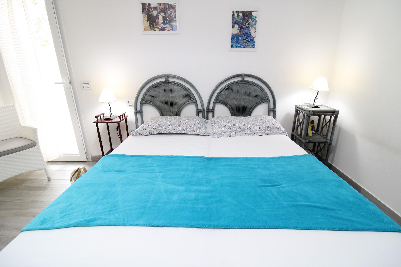 Schlafzimmer mit Doppelbett, zwei Nachttischen und Fenster.