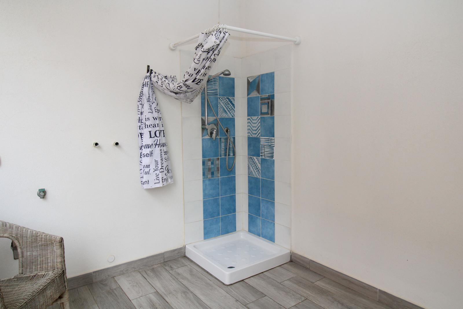 Dusche mit blauen Fliesen und Duschvorhang an der Wand.