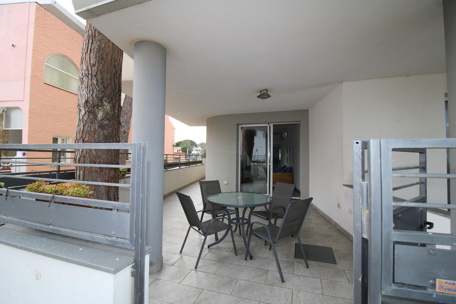 Terrasse mit Tisch und Stühlen, Sicht auf Wohnbereich und Baum.