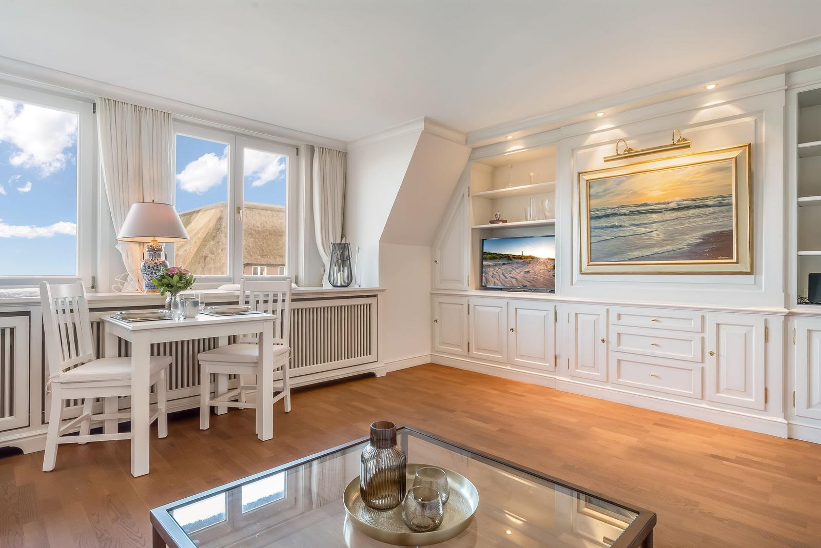 Wohnzimmer mit Essbereich, TV und Blick auf Dachziegel.