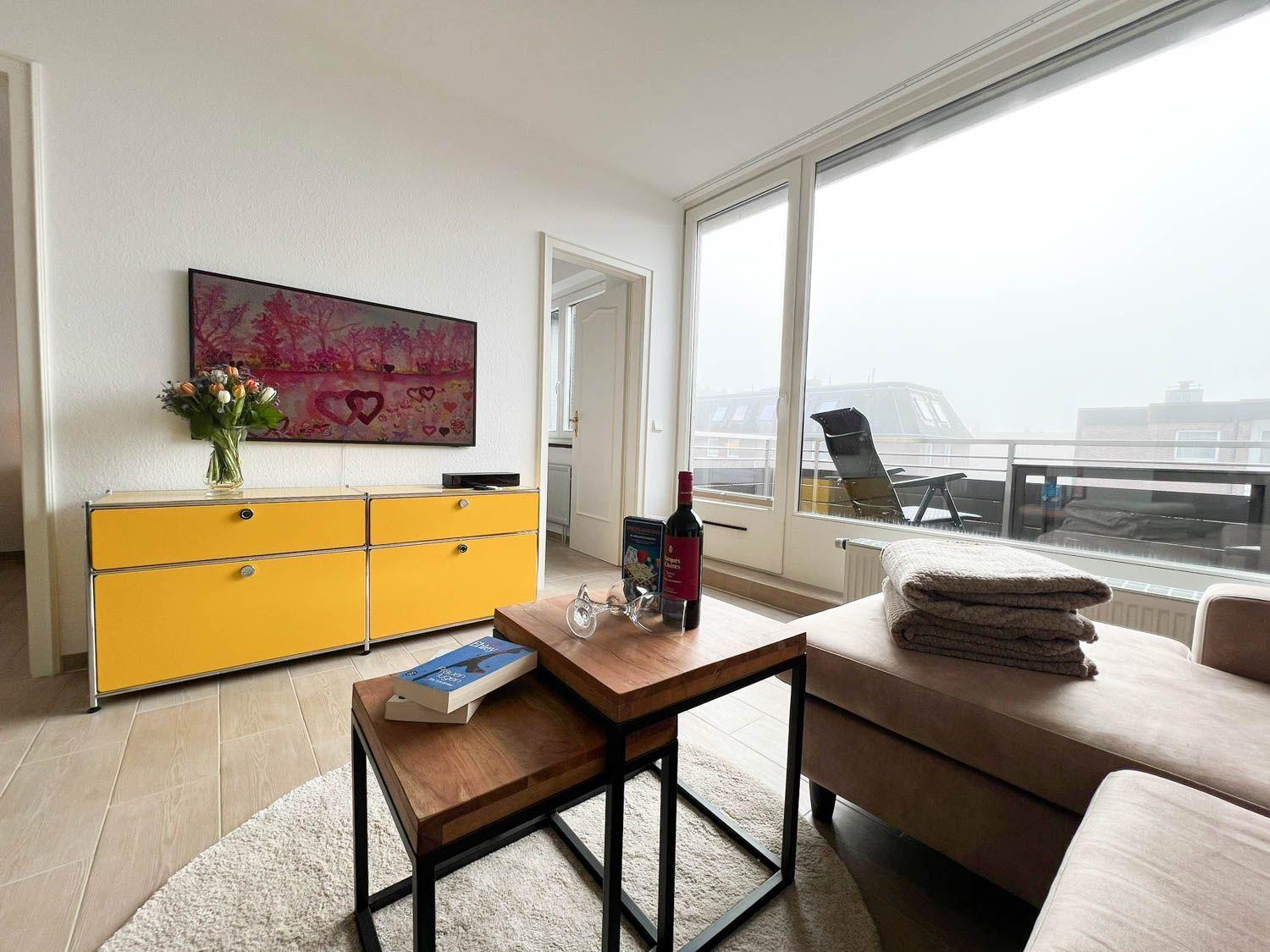 Wohnzimmer mit gelbem Schrank, Couch und Balkonansicht