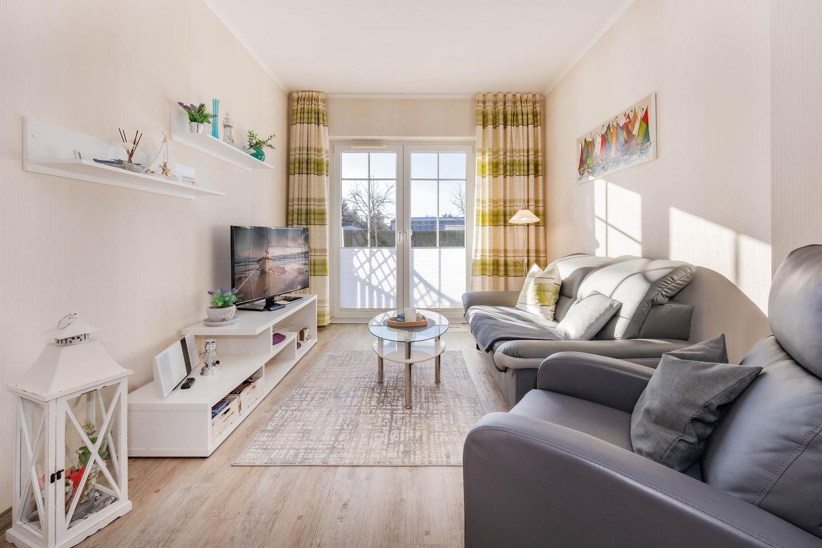 Wohnzimmer mit Sofa, Fernseher und Terrassentür.
