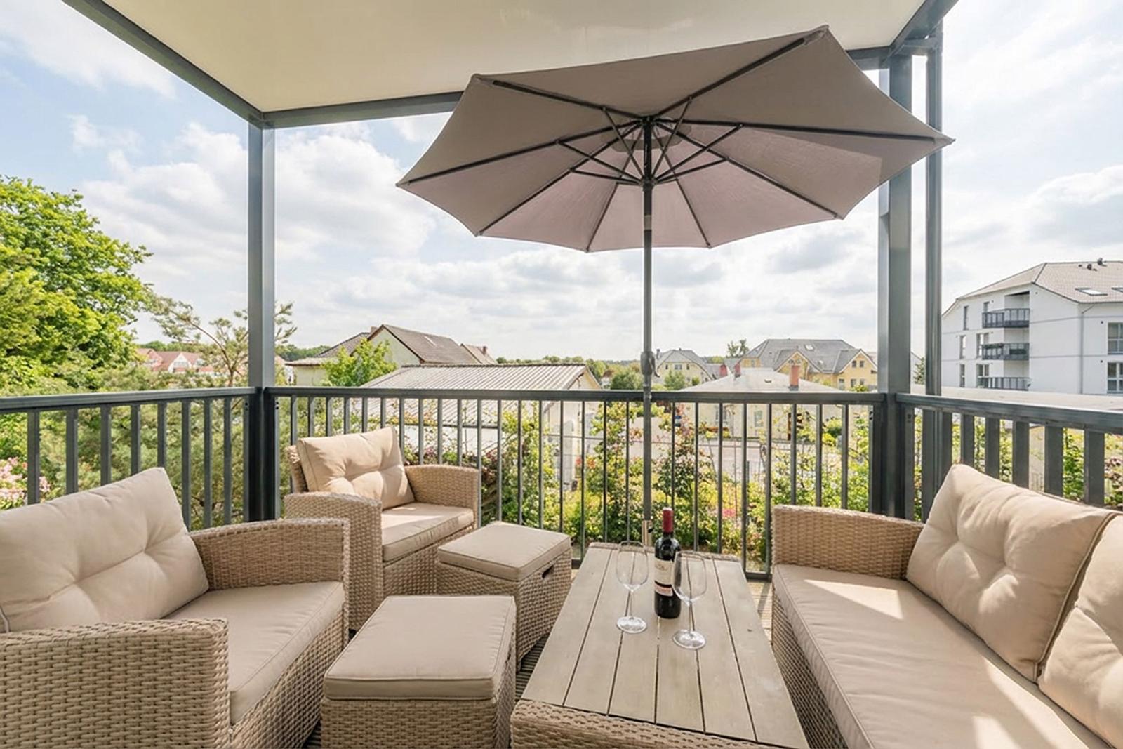 Terrasse mit Sitzgruppe, Sonnenschutz und Tisch mit Weinflasche.
