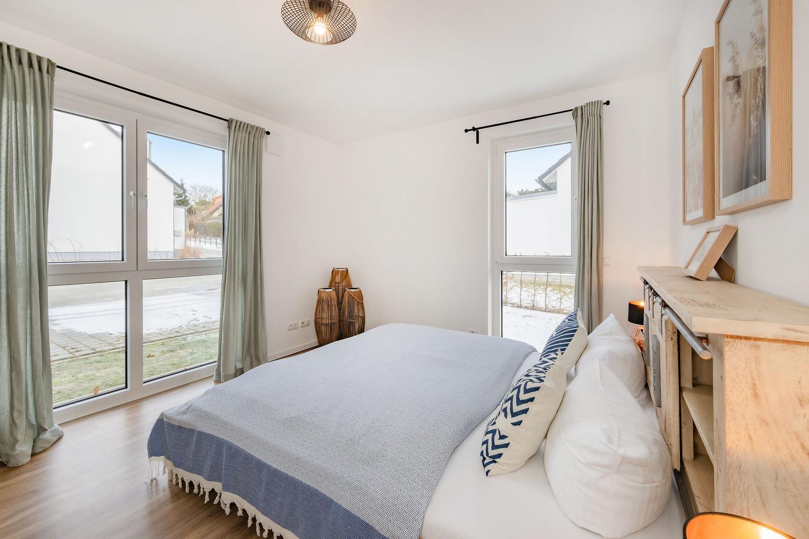 Schlafzimmer mit Bett, Fenstern und Holzboden.
