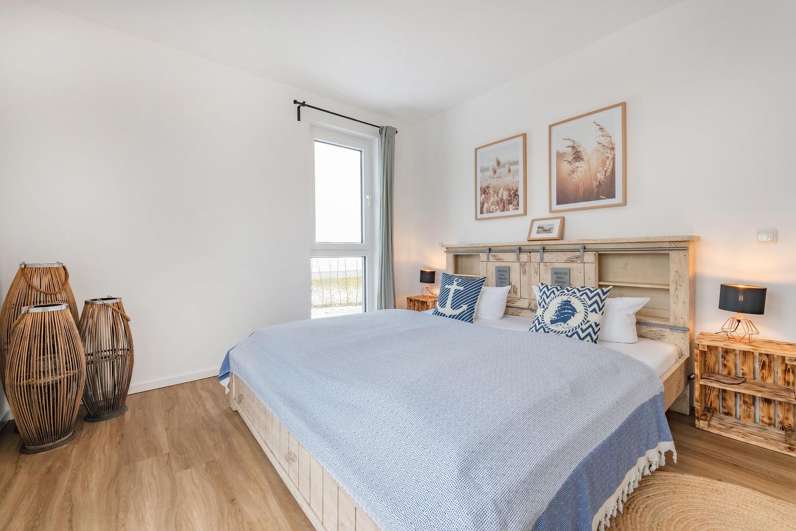 Schlafzimmer mit Bett, Fenster und Wandbildern.