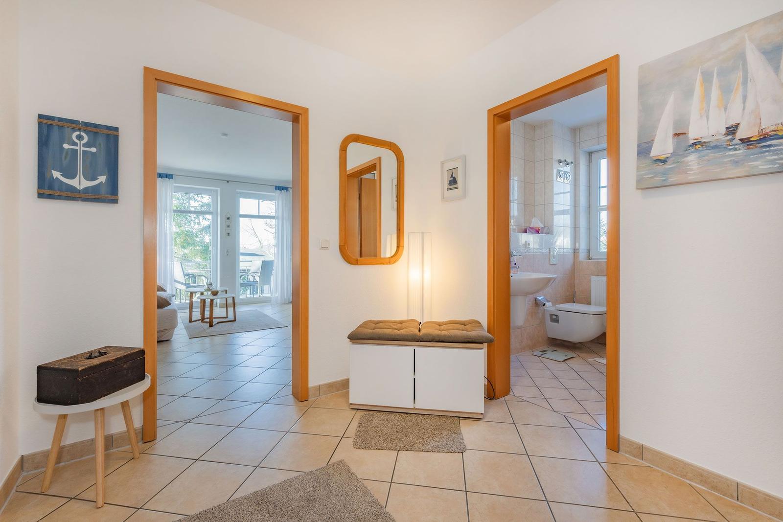 Hausflur mit Blick in Wohnzimmer und Bad, Wandbild Segelboote, Spiegel und Holzrahmen