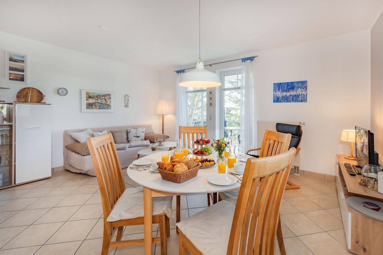 Esszimmer mit Tisch, Stühlen und Frühstück. Wohnbereich mit Sofa und Fenster.