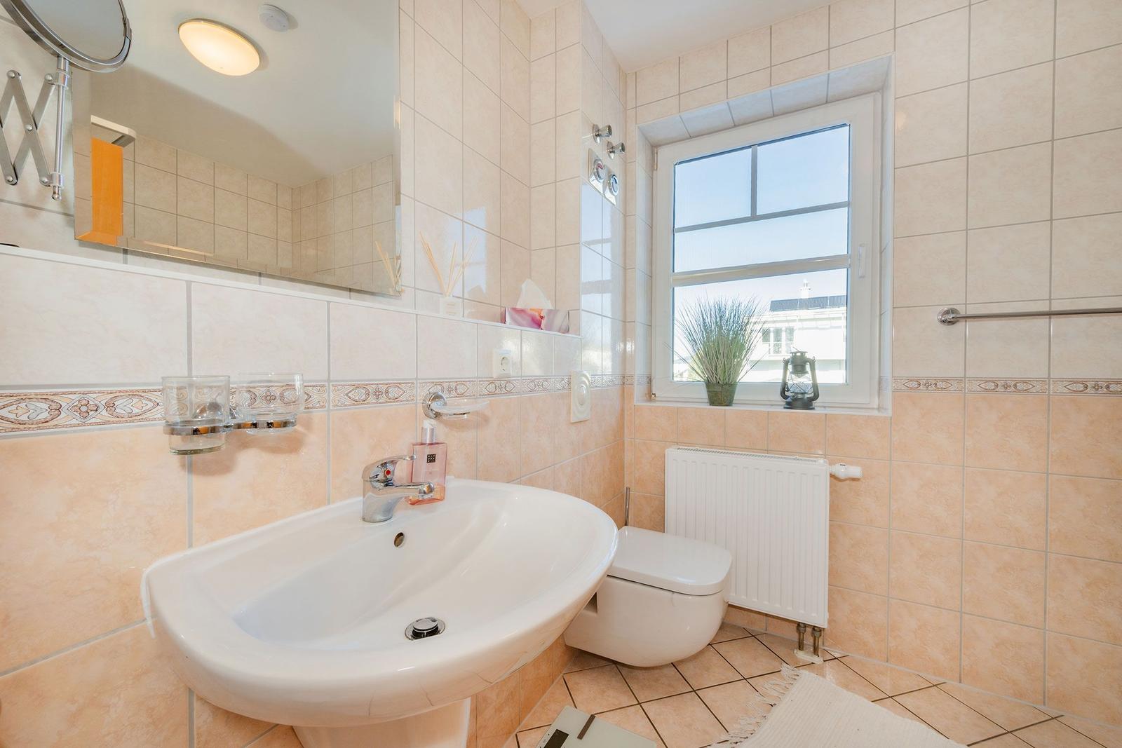 Bad mit Waschbecken, Toilette und Fenster mit Pflanze.