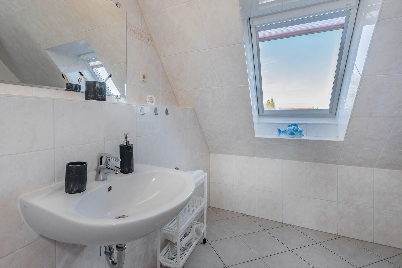Badezimmer mit Waschbecken, Spiegel und Dachfenster.
