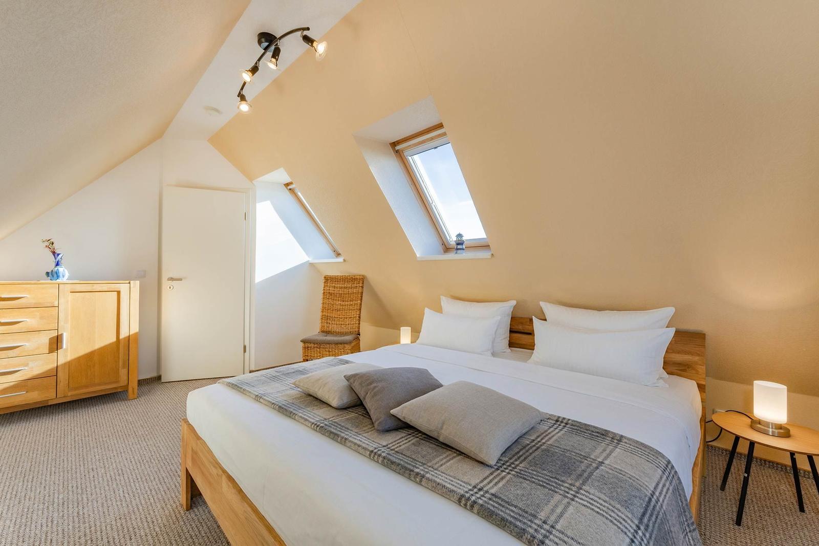 Schlafzimmer mit Dachschrägen, Dachfenster, Bett und Schrank.