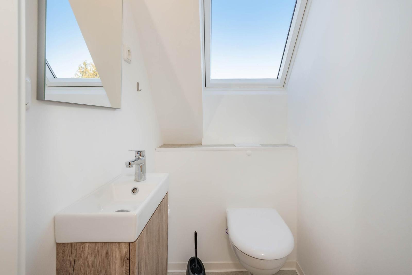 Badezimmer mit Waschbecken, Toilette und Dachfenster.