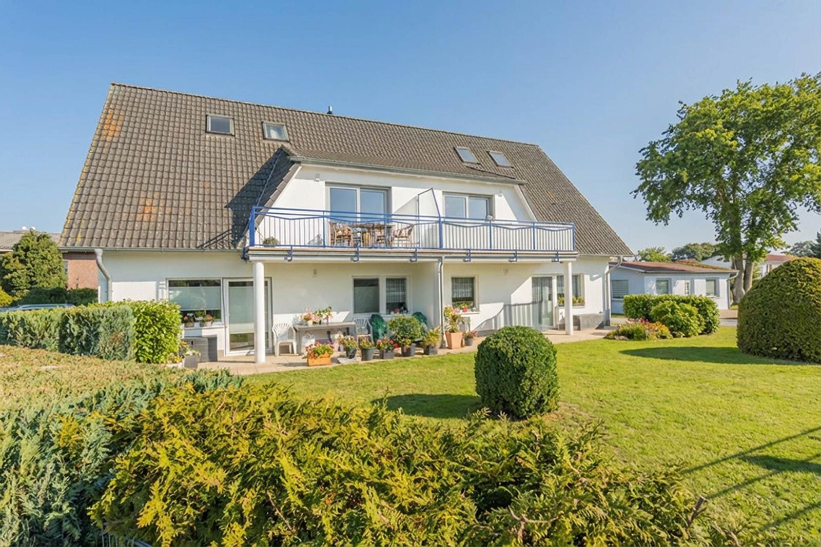 Einfamilienhaus mit Balkon, Garten und Pflanzen. Modernes Design mit großen Fenstern.