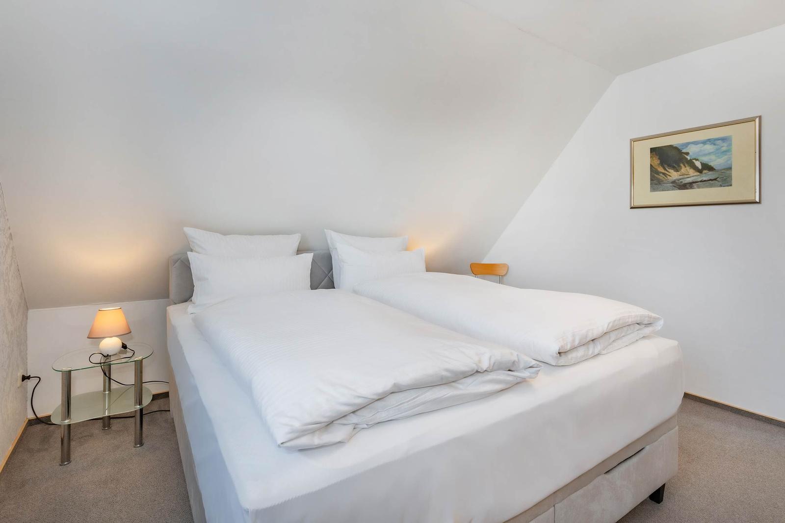 Schlafzimmer mit Doppelbett, Nachttisch und Wandbild.