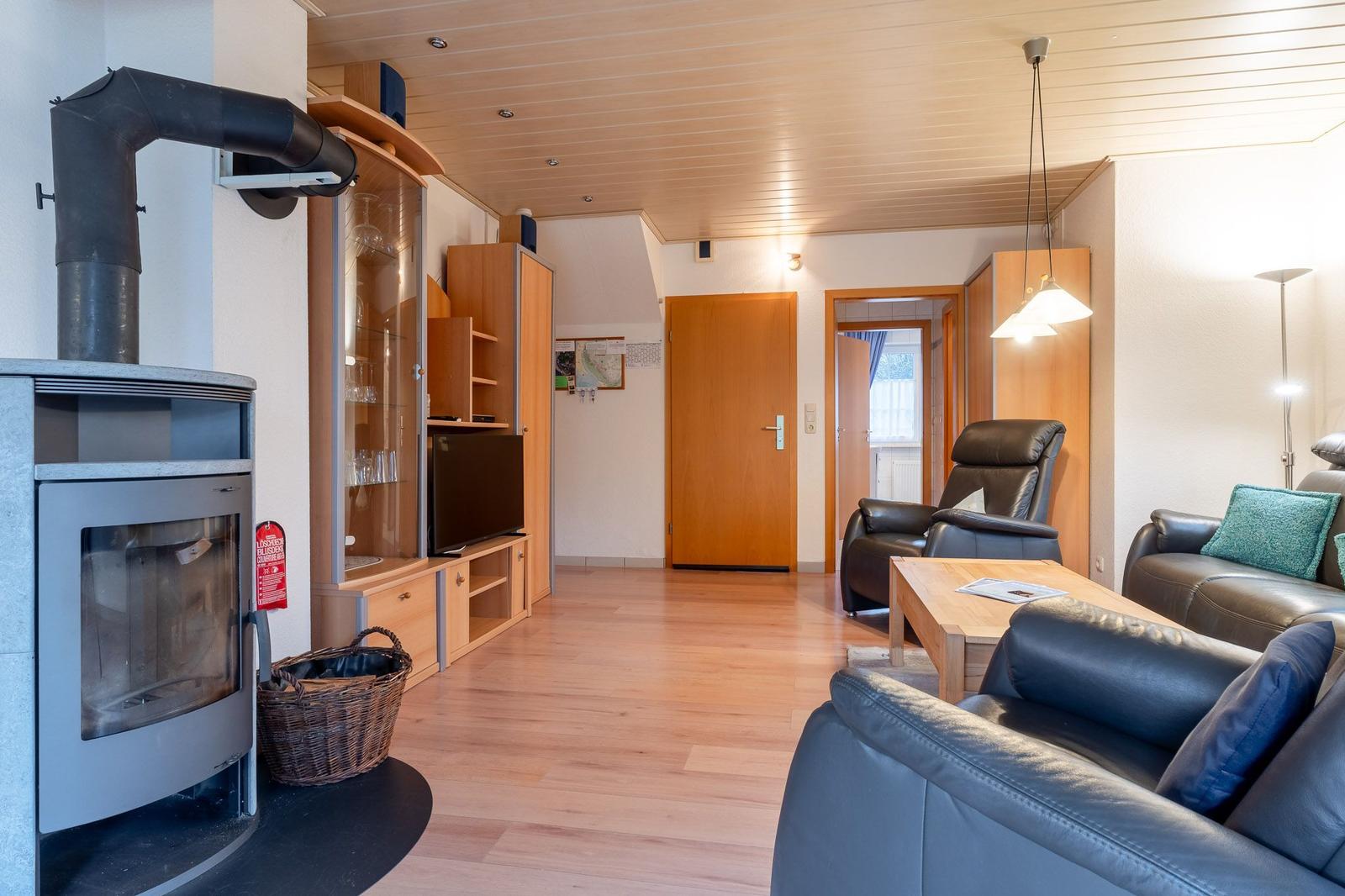 Wohnzimmer mit Holzboden, Kamin, Ledersofa und Fernseher.