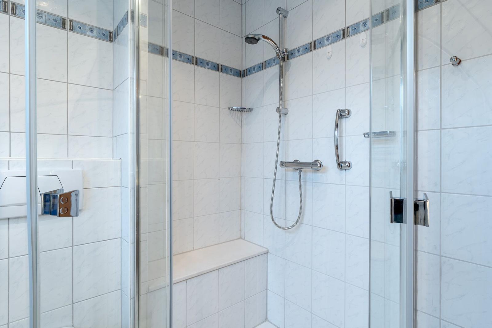 Dusche mit Glaswand, Sitzbank und Duschbrause