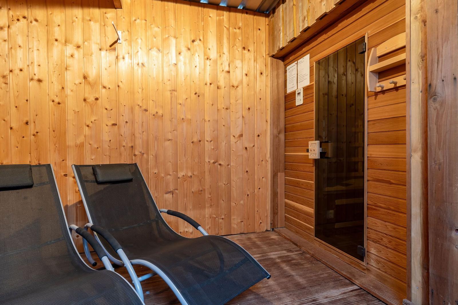 Saunaraum mit zwei Liegestühlen und Holzwandverkleidung.
