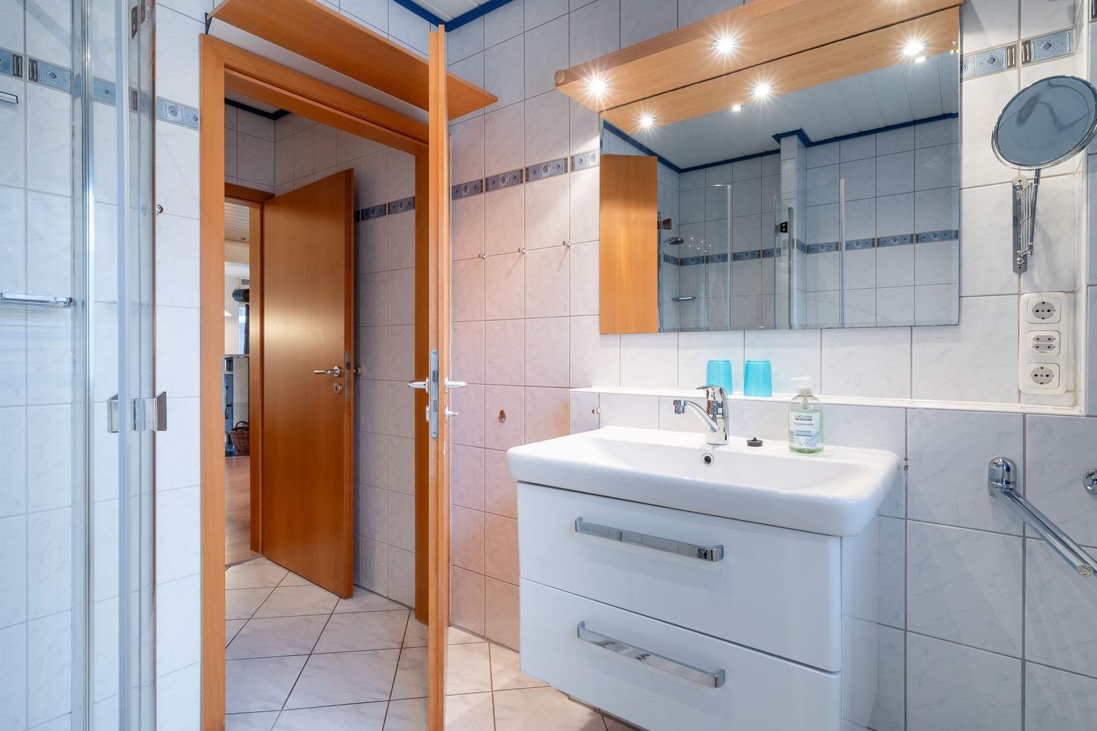 Badezimmer mit Waschbecken, Spiegel und Dusche