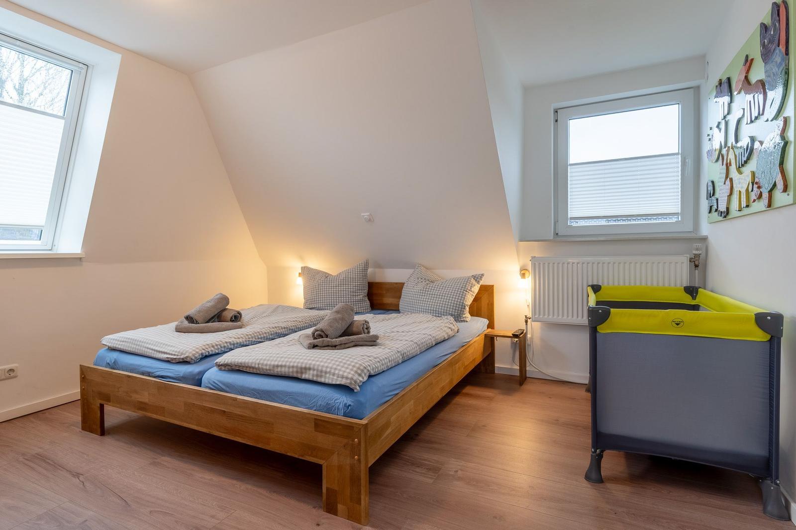 Doppelbett mit blauen Matratzen, Kinderbett und zwei Fenster