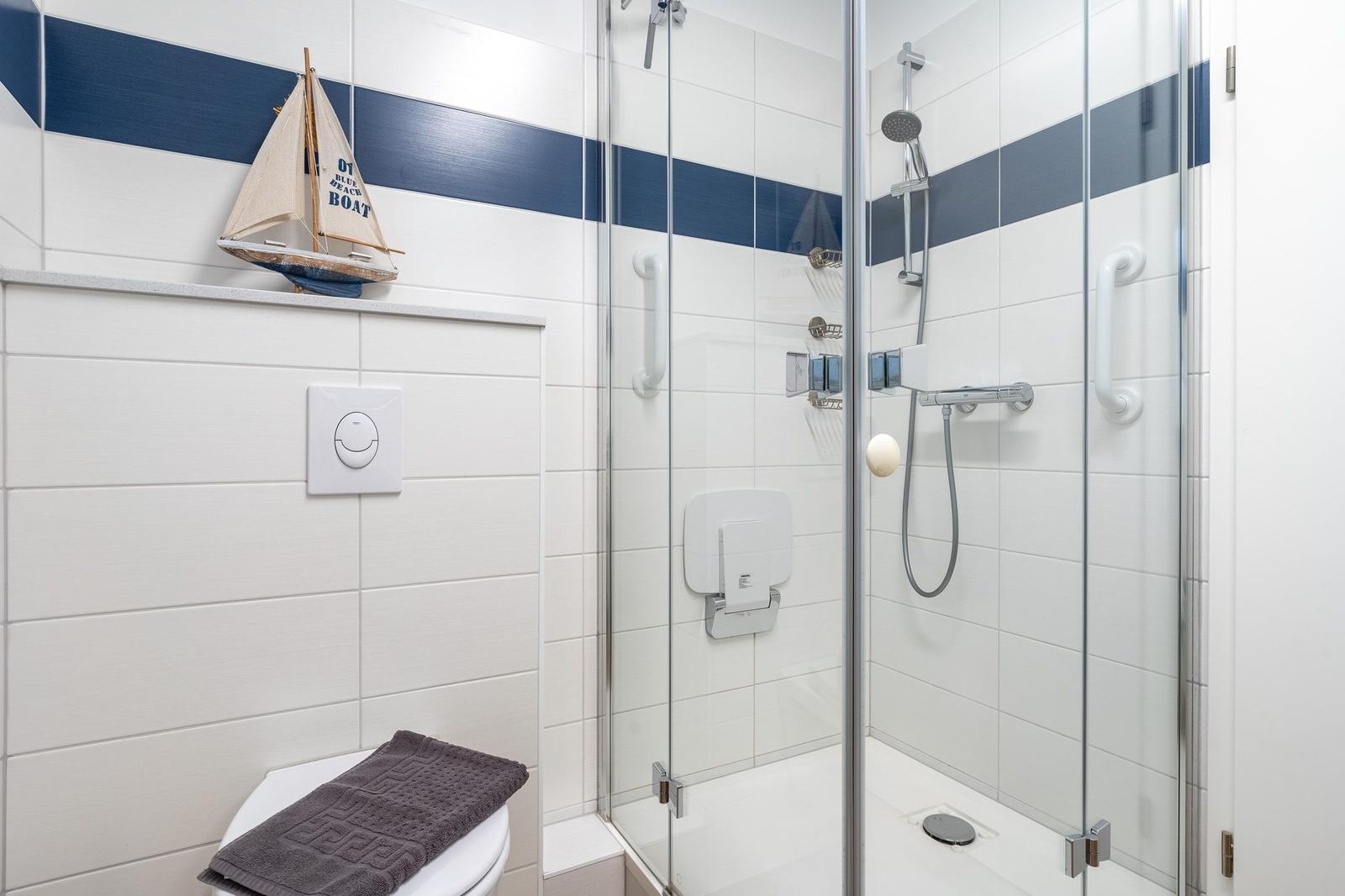 Badezimmer mit Dusche, Toilette und Segelboot-Dekoration.