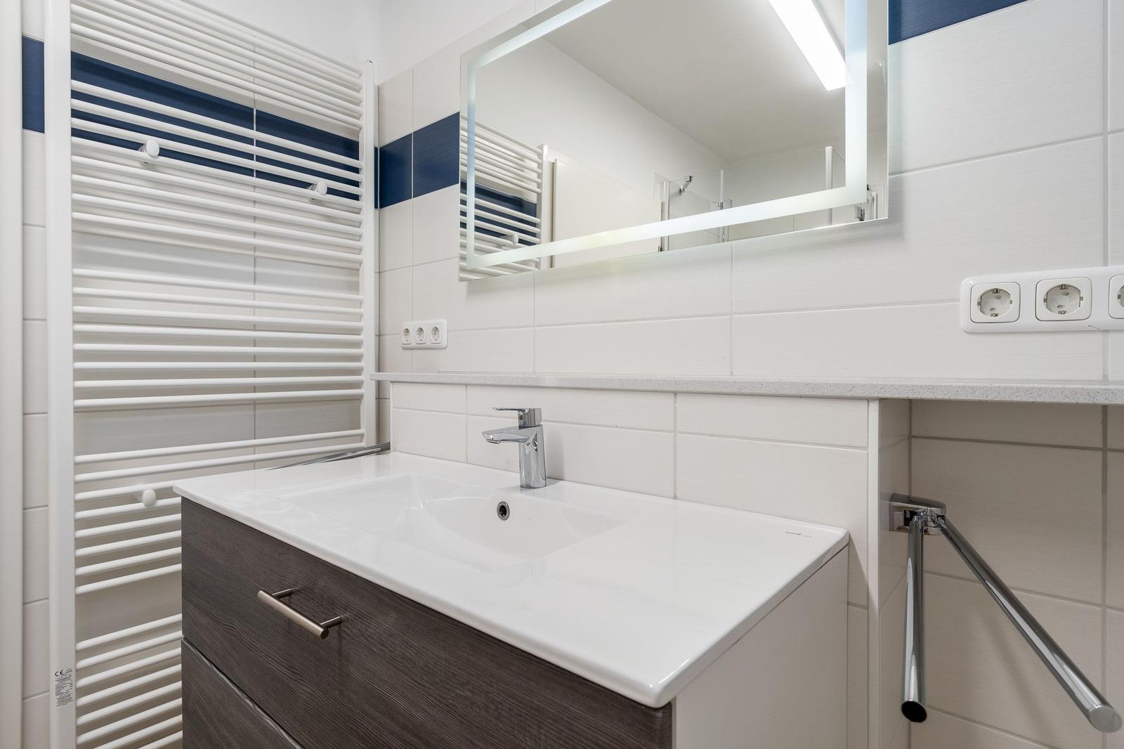 Badezimmer mit Waschbecken, Spiegel und Heizkörper