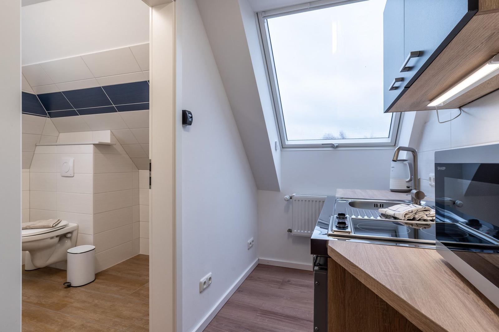 Küche mit Fenster und angrenzender Toilettenstube.
