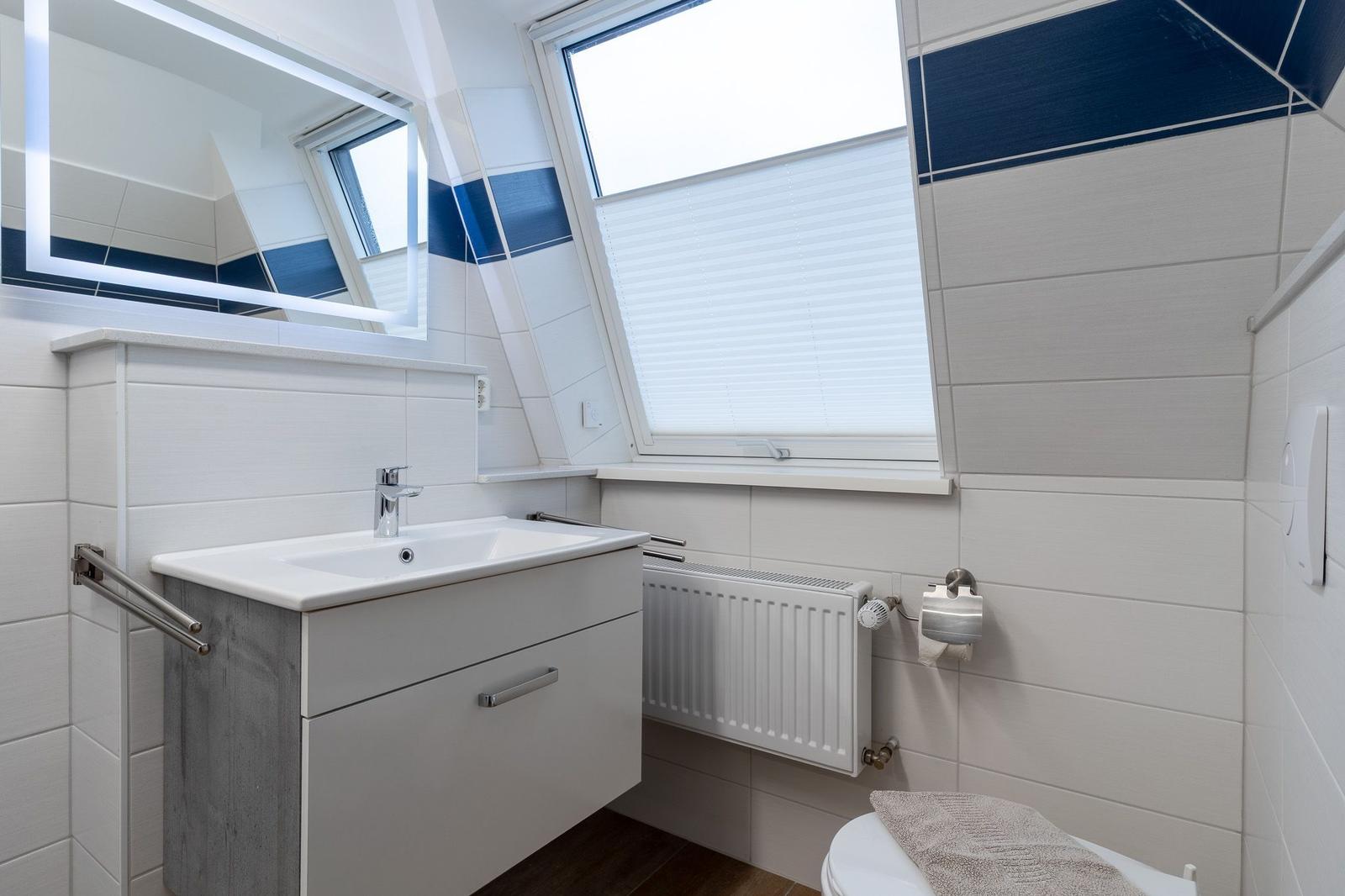 Badezimmer mit Waschbecken, Spiegel und Dachfenster.