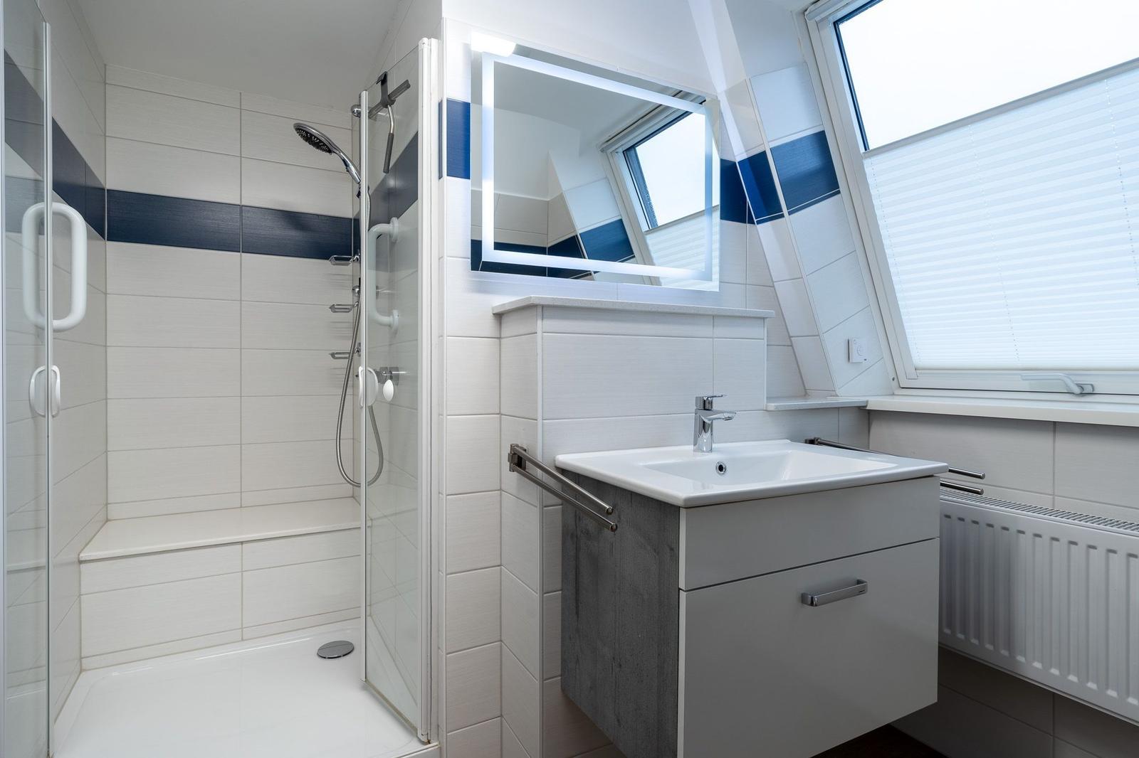 Badezimmer mit Dusche, Waschbecken und Spiegel unter Dach