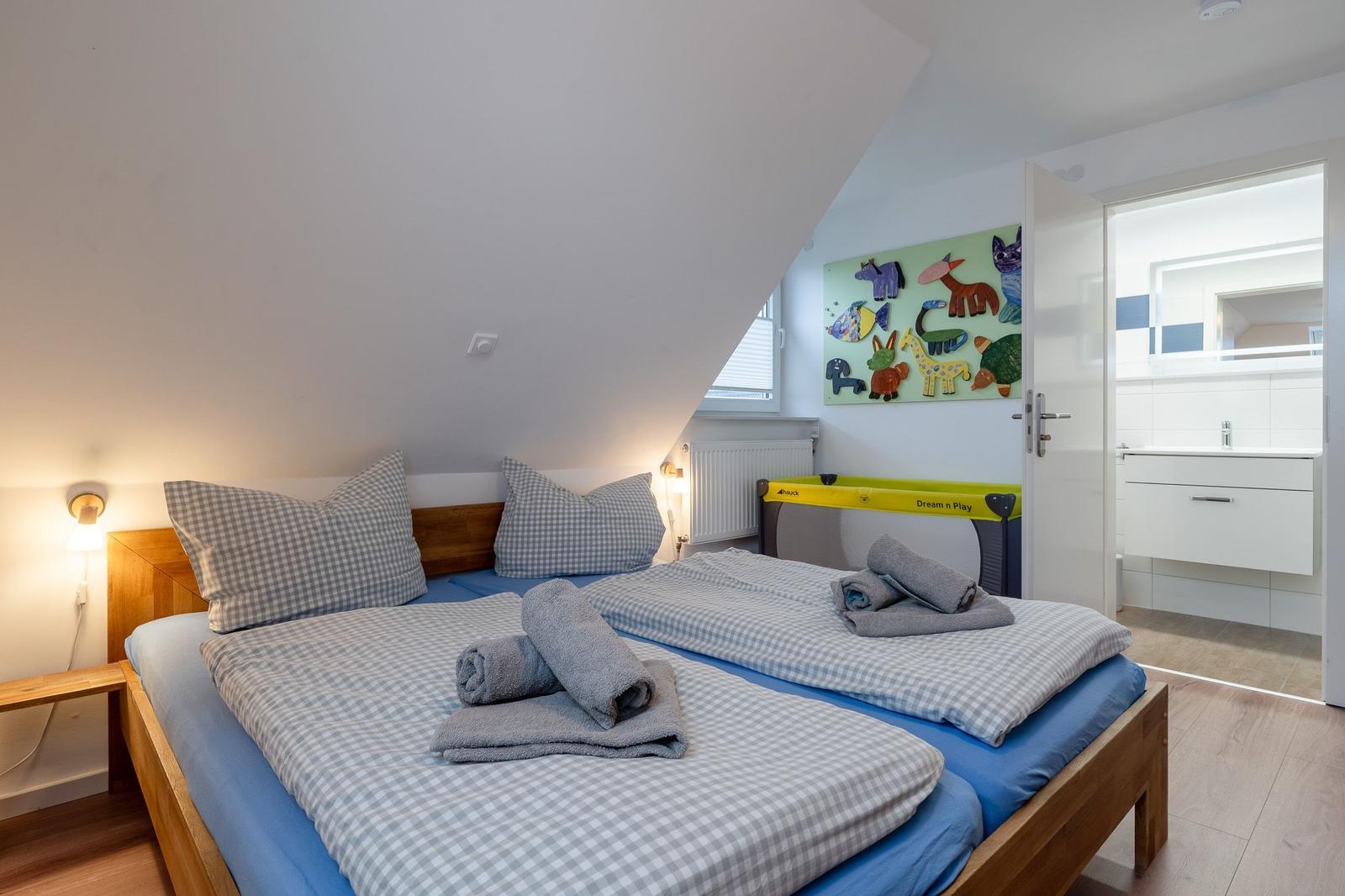 Schlafzimmer mit Doppelbett, Spielwand und angrenzender Badewanne.