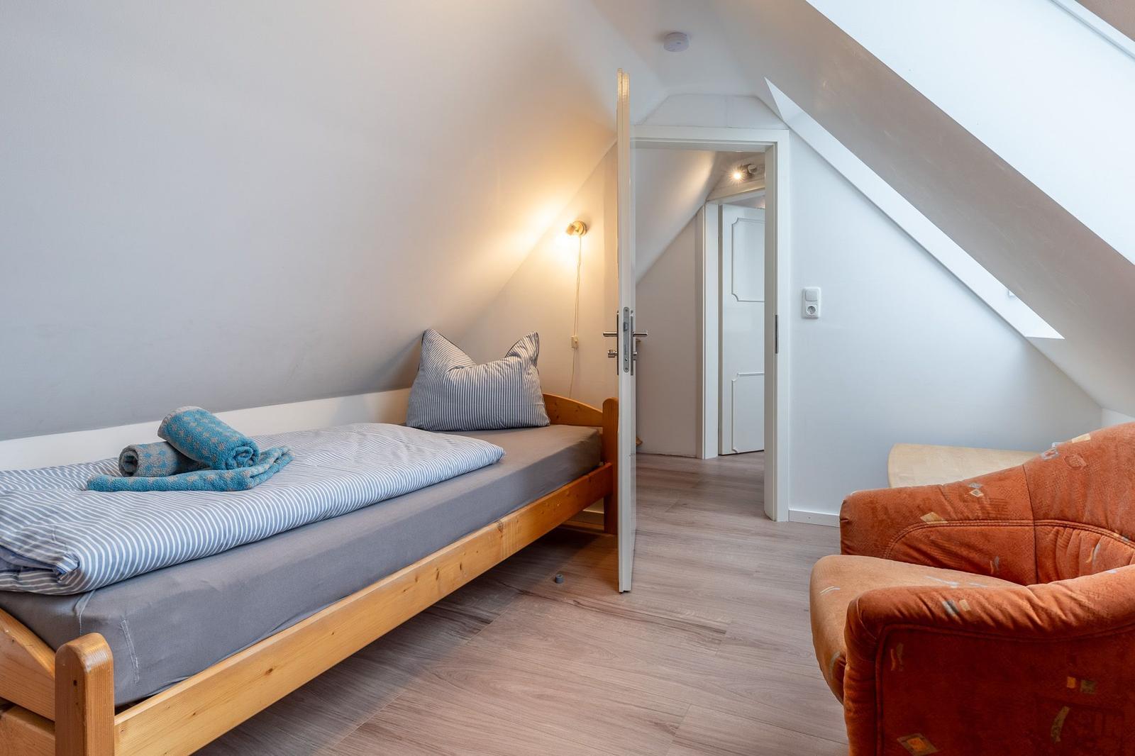 Schlafzimmer mit Dachschrägen, Bett und Sessel