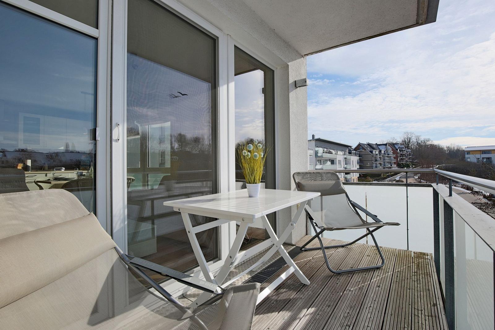 Terrasse mit Tisch, zwei Stühlen und Blick auf Wohngebiet.