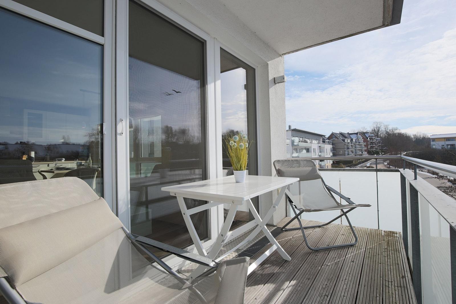 Terrasse mit Tisch, zwei Stühlen und Blick auf Wohngebiet.